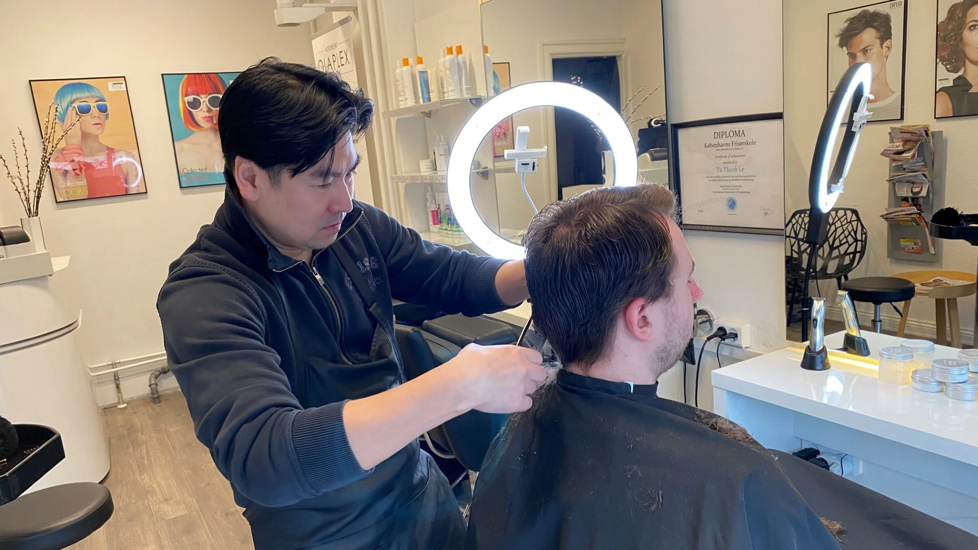 Picture of the owner focusing deeply on a haircut he is giving to a younger gentleman